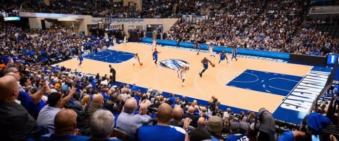 A basketball court with players on it, surrounded by a crowd of spectators.