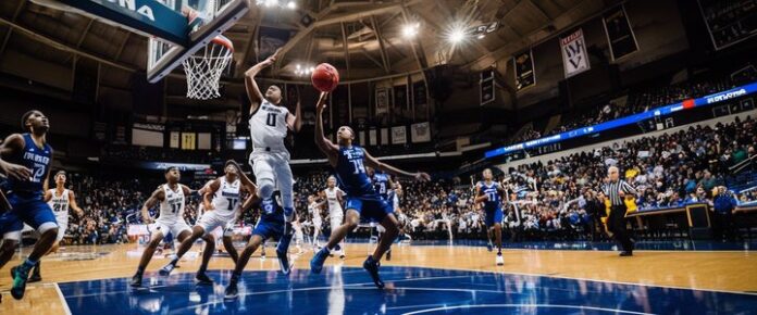 A group of basketball players in white and blue uniforms compete in a game.
