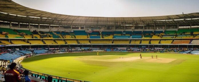 A large, empty stadium with a green field and a few people on it.