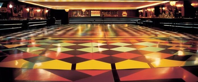 People dancing at Wigan Casino under flashing lights and disco balls.