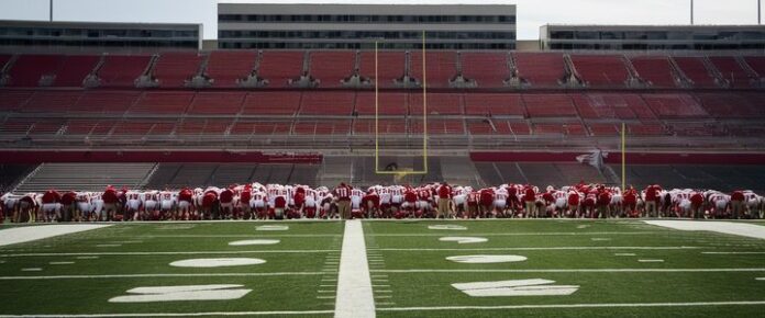 Wisconsin football coach shaking hands with 2026 defensive lineman recruit.